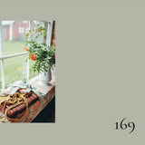 Floral arrangement on a windowsill with a number '169' on a plain background