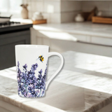 White mug with a floral design featuring lavender and a bee on a marble countertop in a kitchen.