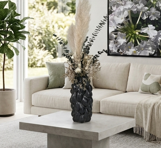 Modern living room with a floral painting, beige sofa, showcasing a dried floral arrangement in a beautiful vase.