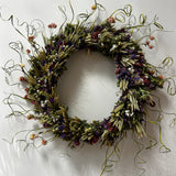 Decorative 30 inch dried floral wreath with vibrant statice and helichrysum and the whimsical texture of various grains, and curly ting ting on a white background