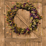 Decorative 30 inch dried floral wreath with vibrant statice and helichrysum and the whimsical texture of various grains, and curly ting ting on a wooden door.