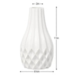 White ceramic vase with a fluted neck and faceted textured base, shown with dimension labels indicating 2 in top diameter, 11 in height, and 6 4/5 in base diameter.