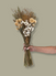 Bouquet of dried flowers held by a hand against a plain background