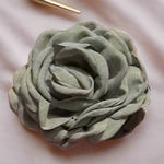 Soft green fabric floral hair clip on cream coloured background