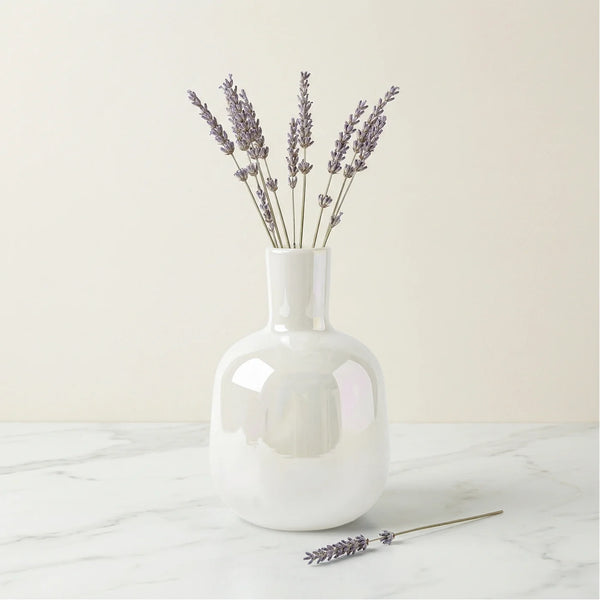 Mini bud vase features a sleek bottle shape and a rainbow lustre glass finish that catches the light beautifully. Shown here with sprigs of lavender on a white marble table with a white background.