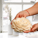 Handcrafted candle with intricate detailing of the elegant peony shape made from 100% pure vegan soy wax. In this image it being held by to hands to demonstrate it's large scale size.