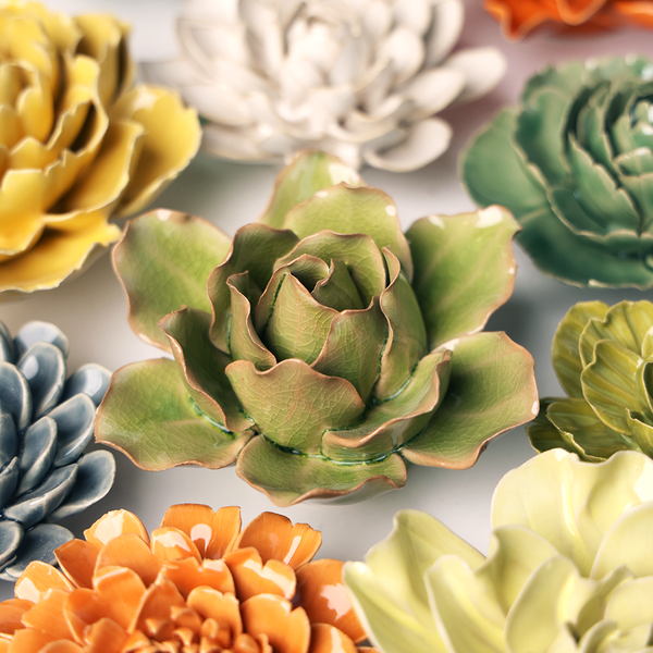 Colorful ceramic flowers in various shapes and sizes on a neutral background
