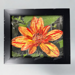 Matte black framed fine art photography of a red and yellow Dahlia flower with green leaves.