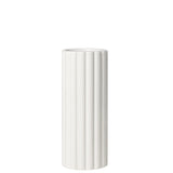 A tall cylindrical vase, whose silhouette is softened by delicate vertical ribbing, creating subtle movement as light shifts across its glossy white surface. 