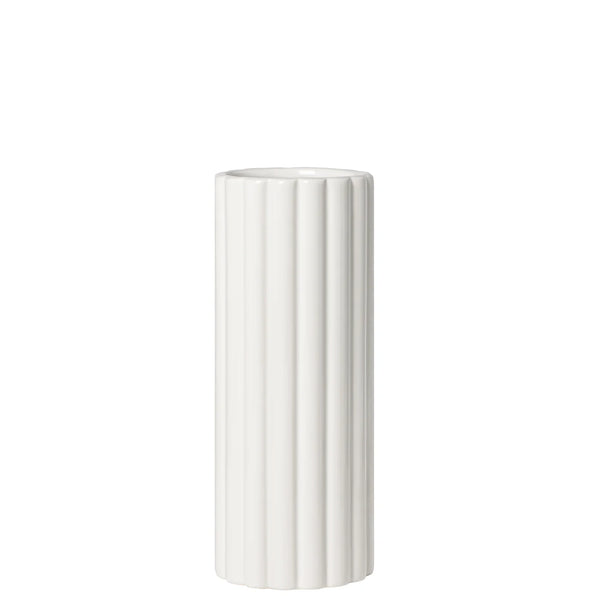 A tall cylindrical vase, whose silhouette is softened by delicate vertical ribbing, creating subtle movement as light shifts across its glossy white surface. 
