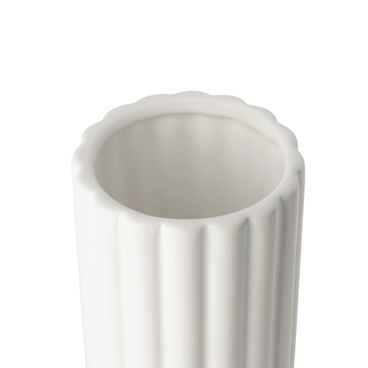A close-up of the opening of a tall cylindrical vase, whose silhouette is softened by delicate vertical ribbing, creating subtle movement as light shifts across its glossy white surface. 