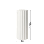 A tall cylindrical vase, whose silhouette is softened by delicate vertical ribbing, creating subtle movement as light shifts across its glossy white surface with it's dimensions of 4 inches in diameter and 9.75 inches tall.