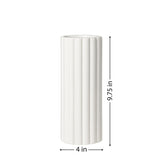 A tall cylindrical vase, whose silhouette is softened by delicate vertical ribbing, creating subtle movement as light shifts across its glossy white surface with it's dimensions of 4 inches in diameter and 9.75 inches tall.