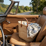 Woven basket with a floral blanket on a car seat with a scenic road in the background
