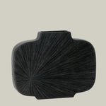 A striking, sculptural wide vase in midnight-cocoa with a bold, radiating carved pattern that starting in the bottom left corner. 