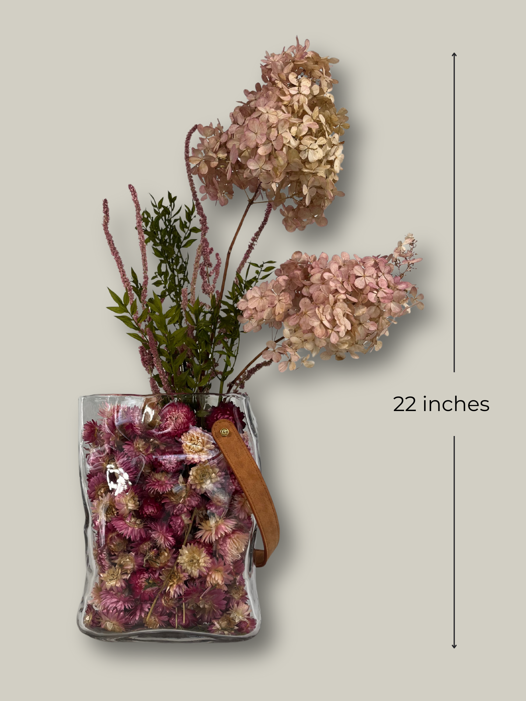 Clear glass vase shaped like a bag with dried flowers and a measurement label stating 22 inches high on a neutral background
