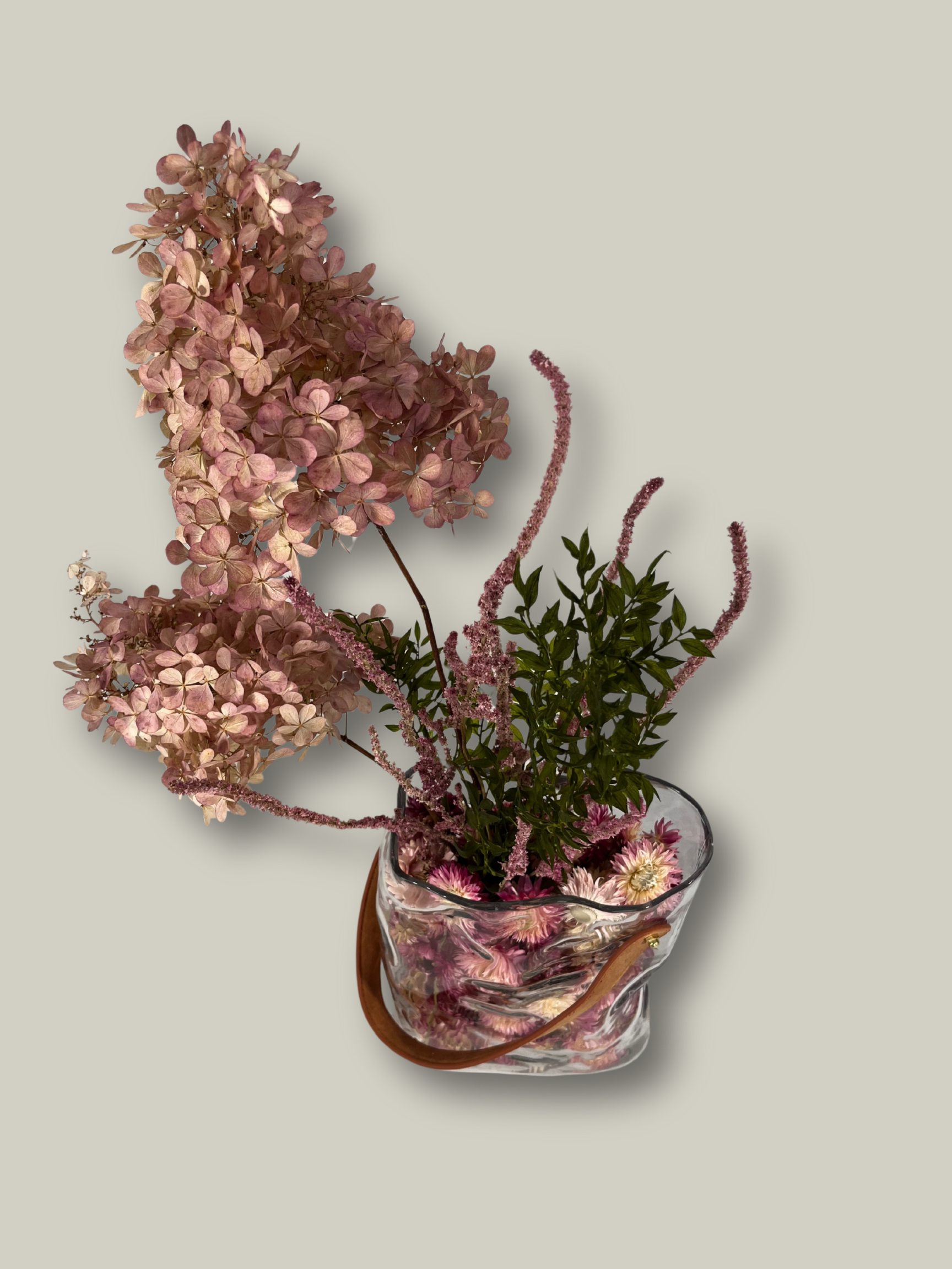 Decorative arrangement of flowers in a glass vase on a light gray background