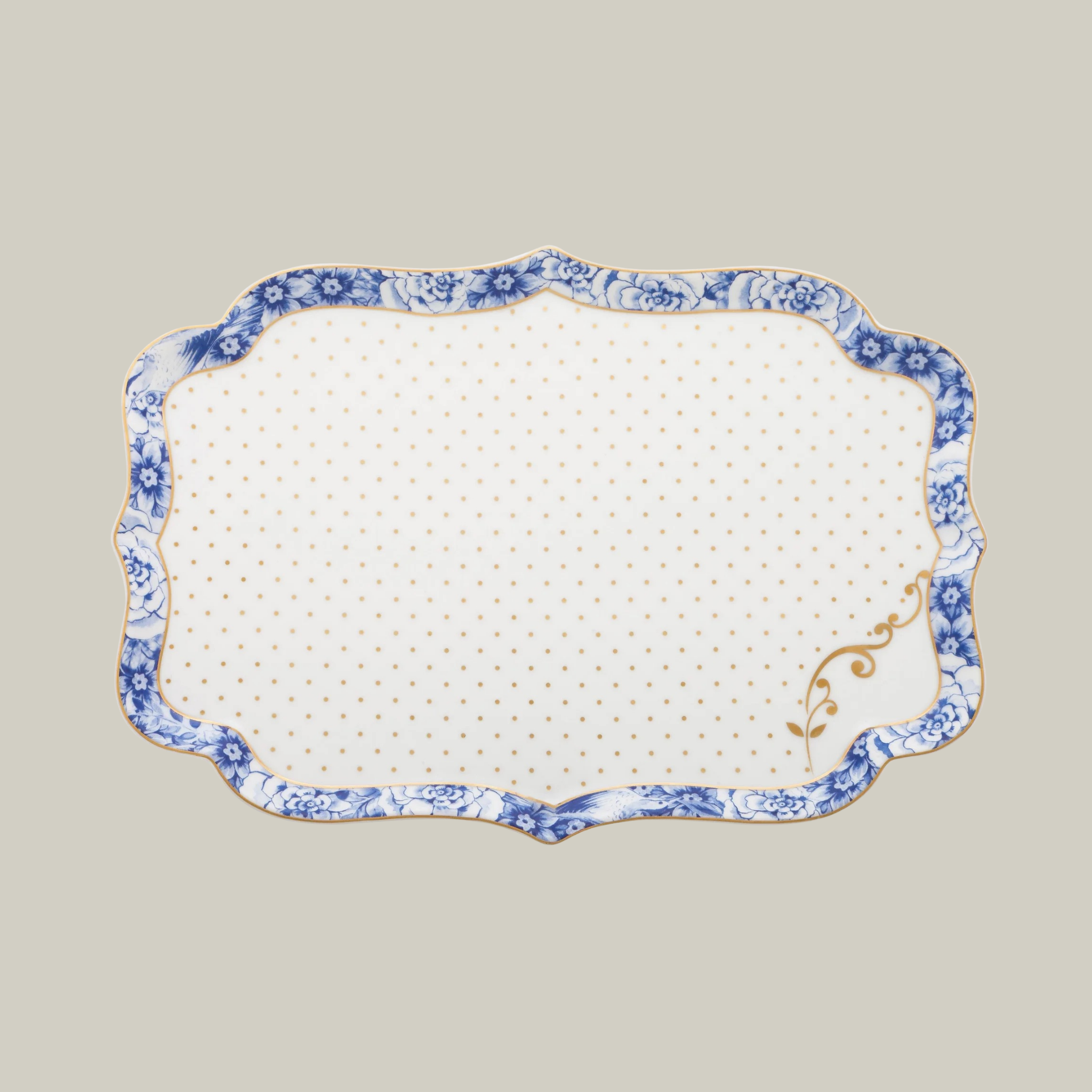 Rectangular porcelain white serving plate with gold and blue floral patterns on a soft green background