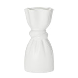 White ceramic vase with a delicate cinch midway that creates a graceful twist on a white background.