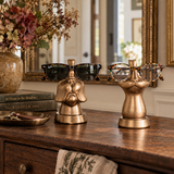 Two decorative metallic gold sunglasses and eyeglasses stands displayed on a wooden console table in a styled interior setting.