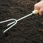 Hand holding a garden fork in dark soil