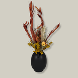 Side view of a magnificent 30" dried floral arrangement with autumn botanicals like helichrysum, dahlias, & oak leaves in a matte brown urn.