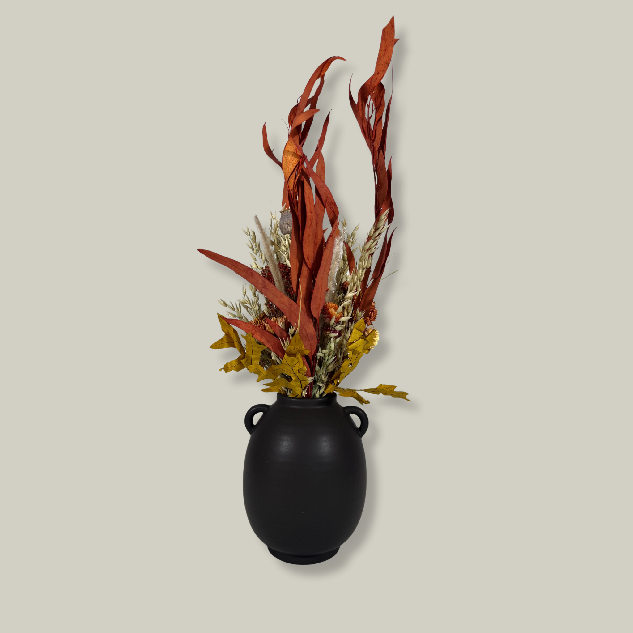Back view of a magnificent 30" dried floral arrangement with autumn botanicals like helichrysum, dahlias, & oak leaves in a matte brown urn.
