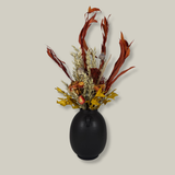 Side view of a magnificent 30" dried floral arrangement with autumn botanicals like helichrysum, dahlias, & oak leaves in a matte brown urn.