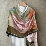 Floral patterned scarf draped over a white shirt on a wooden hanger against a beige background