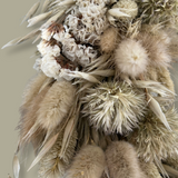 A close-up view of an exquisite 10-inch wreath made with lush white Statice, airy natural Oat Grass, feathery Lagers ovatus, and more creamy blooms.  