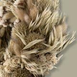 A close-up of an exquisite 10-inch wreath made with lush white Statice, airy natural Oat Grass, feathery Lagers ovatus, and more creamy blooms. 