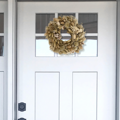 Exquisite 10-inch wreath made with lush white Statice, airy natural Oat Grass, feathery Lagers ovatus, and more creamy blooms on a white door with a window.