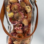 Decorative glass vase shaped like a paper bag with a leather handle filled with dried helichrysum in a natural salmon colour.