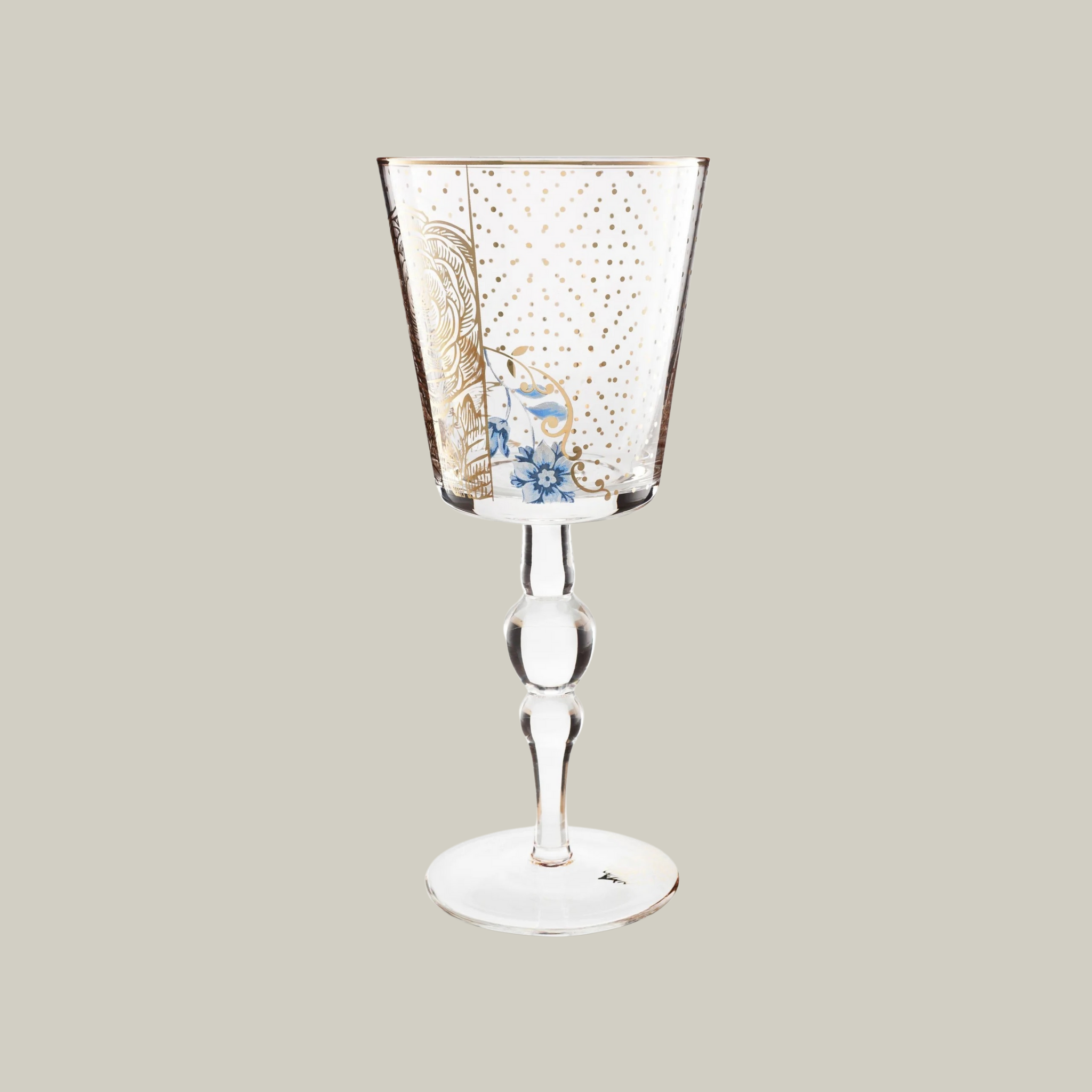 Wine glass with with gold floral and poke-a-dot design on a soft green background