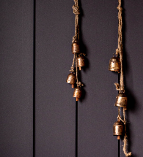 Set of hanging brass bells against a dark wooden panel background