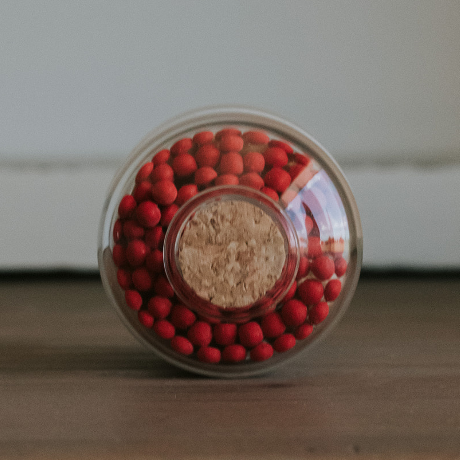 Jar filled with red matchsticks on a wooden surface with a neutral background