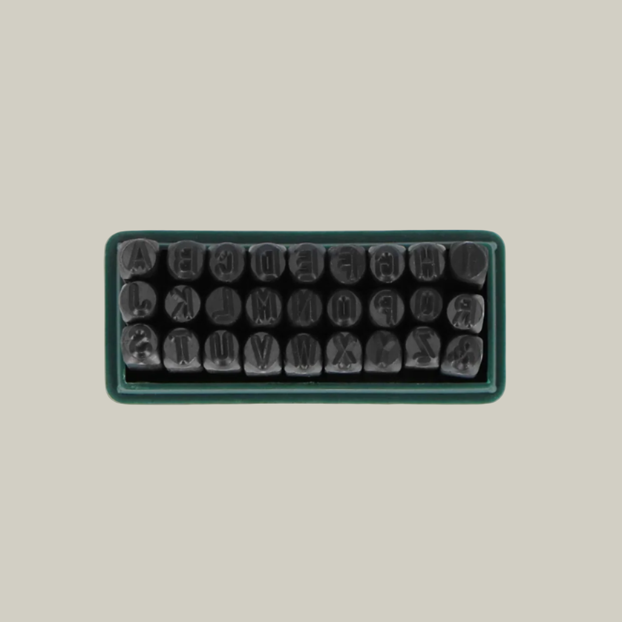 Set of metal stamps in a rectangular tray on a light green background