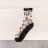 Sheer floral socks with black ruffle top and sole on a light background
