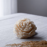 Beautiful small candle in the shape of a peony flower on a wooden surface. 