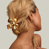 Woman with a gold hair clip and earring against a beige background