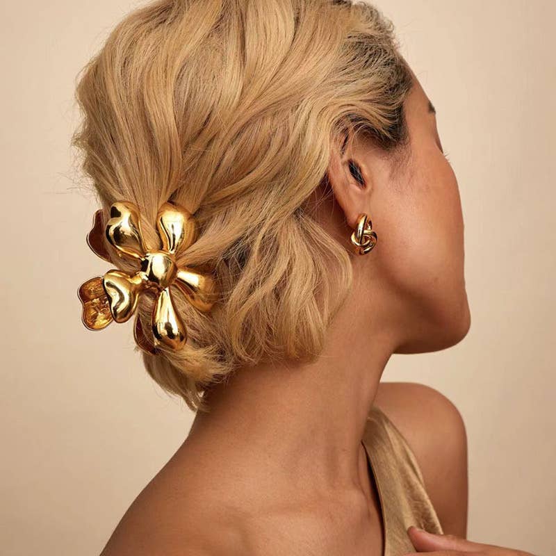 Woman with a gold hair clip and earring against a beige background