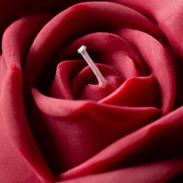 Close-up of a beautiful handcrafted candle with intricate detailing of a red rose shape made from 100% pure vegan soy wax. 