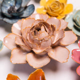 Close-up of a pink ceramic sculpture of a Camellia flower with other flower sculptures in the background