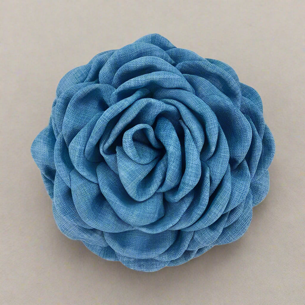 Blue fabric flower hair clip on a cream background