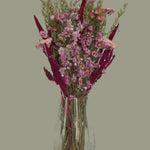 This striking, hand-tied bouquet is a harmonious blend of dried botanicals in deep red, soft pink, and natural oats. 