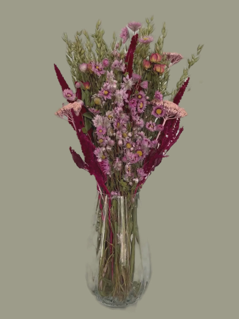This striking, hand-tied bouquet is a harmonious blend of dried botanicals in deep red, soft pink, and natural oats. 