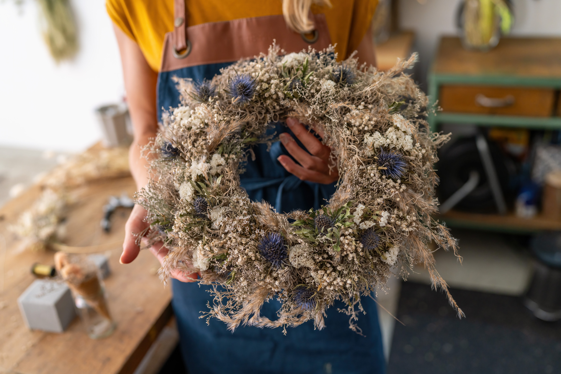 Florist presenting a nearly finished dried flower wreath, showca